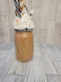 a mason jar filled with whipped cream and chocolate straws on top of a wooden floor