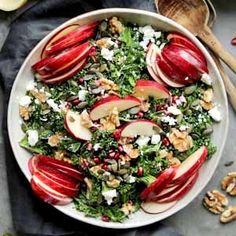 an apple and kale salad with walnuts in a white bowl on a table