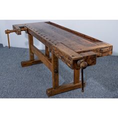 an old wooden work bench sitting on top of a blue carpeted floor next to a white wall