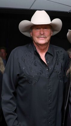 two people standing next to each other wearing cowboy hats on their heads and black shirts