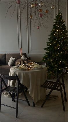 a living room with a christmas tree in the corner and a table set for two