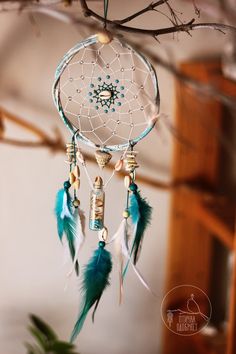 a blue and white dream catcher hanging from a tree branch with beads on it's side