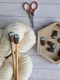 yarn, scissors and other crafting supplies on a white wooden table with wood tray