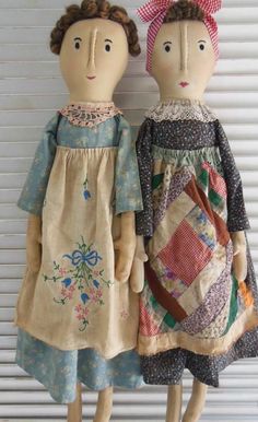 two dolls standing next to each other on a window sill with shutters in the background