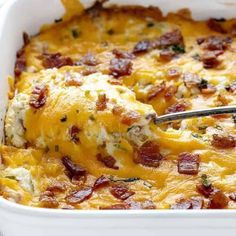 a close up of a casserole dish with bacon and cheese on it, being lifted by a fork