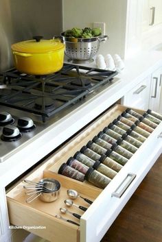 an open drawer in the middle of a kitchen with utensils and bowls on it