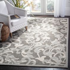 a white chair sitting in front of a window next to a gray rug on top of a hard wood floor