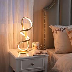 a lamp that is sitting on top of a night stand next to a coffee cup