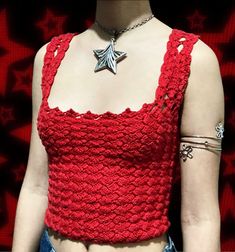 a woman wearing a red crop top with silver stars on it's chest and arm