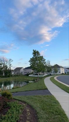 a bench sitting on the side of a road next to a lake and houses in the background