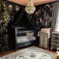 a baby's room decorated in black and white with floral wallpaper, crib, dressers, and chandelier