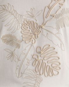 an embroidered white shirt with flowers and leaves on it