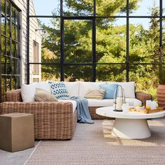 a living room with large windows and wicker furniture