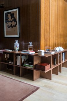 a table with books and vases on it in front of a wooden paneled wall