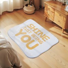 a bathroom rug that says, you shine before you go on the floor next to a bed