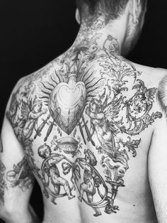 the back of a man with tattoos on his upper and lower half is shown in black and white