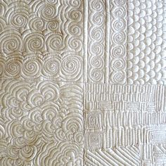 a close up view of a quilt with white threadwork on the back and sides