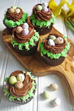 chocolate cupcakes decorated with green icing and mini eggs on a wooden board