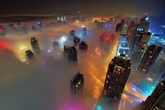 an aerial view of the city at night in foggy conditions with skyscrapers lit up