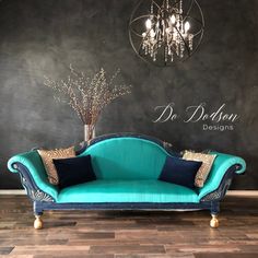 a blue couch sitting on top of a wooden floor next to a chandelier