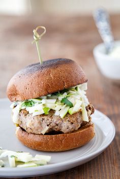 a sandwich with meat, cheese and lettuce on a bun sitting on a plate