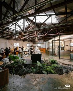 people working in an open office building with lots of plants on the floor and walls