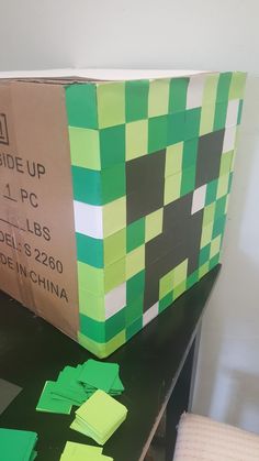 a cardboard box sitting on top of a table covered in green and black paper squares