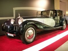 an antique car is on display in a museum with red carpet and white stripes around it