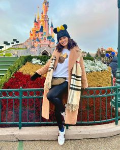 a woman is posing in front of the castle at disney world with her hand on her hip