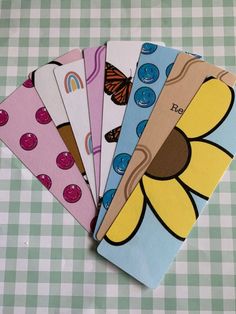 four notebooks are lined up on a checkered tablecloth with flowers and butterflies