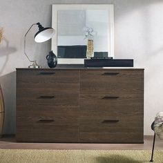 a brown dresser sitting next to a lamp on top of a wooden floor