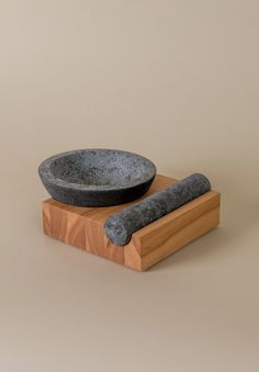 a stone bowl and a wooden stand with a black object on it's side