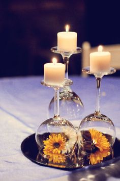 two wine glasses with sunflowers in them are sitting on a plate that is decorated with candles