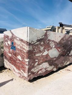 a large marble slab sitting on top of a dirt field next to a building with a blue sky in the background