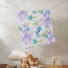 two teddy bears sitting on pillows in front of a wall with a blue flowered blanket