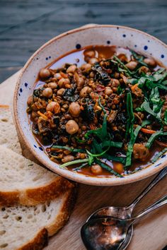 a bowl filled with beans and greens next to two slices of bread