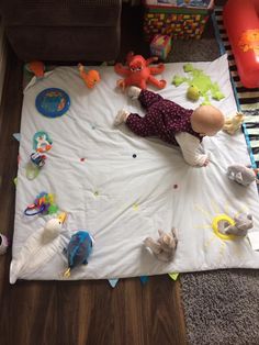 a baby laying on a play mat with stuffed animals