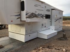 an rv parked on the side of a dirt road with mountains painted on it's sides