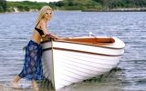 a woman standing in the water next to a boat