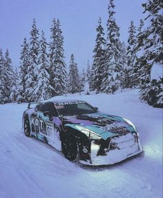 a car that is sitting in the snow with trees behind it and some snow on the ground