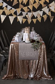 a table with gold sequins, candles and napkins hanging from the ceiling