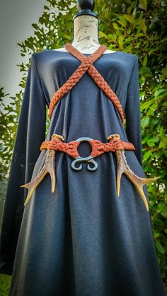 a dress made out of antlers and rope on display in front of some trees