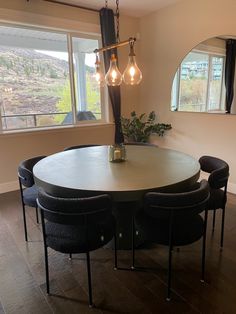 a dining room table with four chairs and a round light fixture hanging from the ceiling