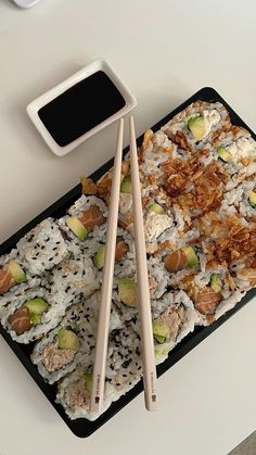 two chopsticks resting on a tray with sushi