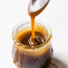 a spoon pouring caramel sauce into a jar