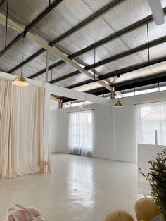 an empty room with white walls and drapes hanging from the ceiling in front of windows