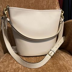 This Iconic Archival Dakota Bucket Bag In A Relaxed Coach Style Is The Epitome Of Laid-Back Sophistication. The Buttery Soft Glovetanned Leather Style Has A Spacious Interior And Is Finished With Two Detachable Straps To Carry By Hand, Style As A Short Shoulder Bag Or Wear Crossbody. (It’s Totally Up To You.). It Equipped With A Inside Zip Pocket And A Snap Closure To Keep Your Things Safe & Secure. Detachable Handle With 10 3/4" Drop Detachable Strap With 21 1/2" Drop For Shoulder Or Crossbody Classic Bucket Shoulder Bag With Gold-tone Hardware, Classic Bucket Bag With Gold-tone Hardware For Formal Occasions, Classic Formal Bucket Bag With Gold-tone Hardware, Classic Cream Bucket Bag With Gold-tone Hardware, Classic Cream Bag For Everyday Luxury, Classic Bucket-shape Shoulder Bag With Detachable Strap, Modern White Bucket Bag With Gold-tone Hardware, Classic Cream Bucket Bag, Luxury Bags With Gold-tone Hardware In Bucket Shape