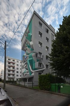 a large white building with blue and green artwork on it's side next to a street