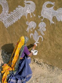 a woman is drawing on the ground with chalk