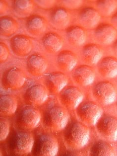 a close up view of the surface of an orange substance with small circles on it